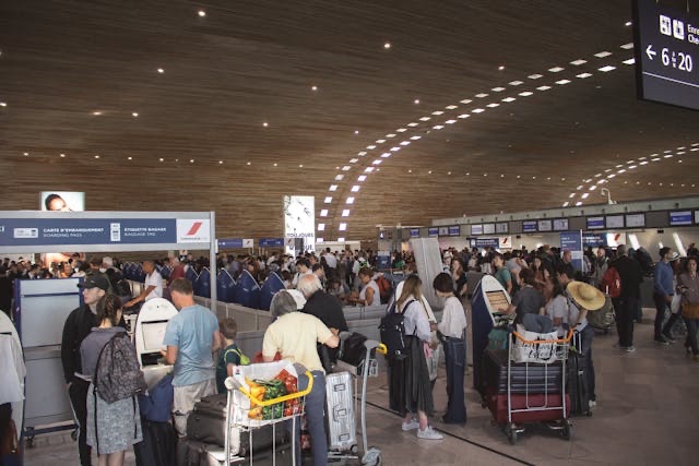 Crowded airport check-in area with travelers waiting in line with luggage carts